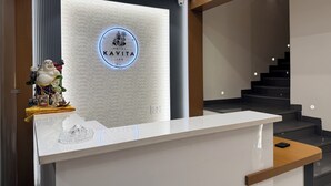 Un mostrador de recepción de hotel con diseño moderno, un logotipo sobre el mostrador y una escalera al fondo.