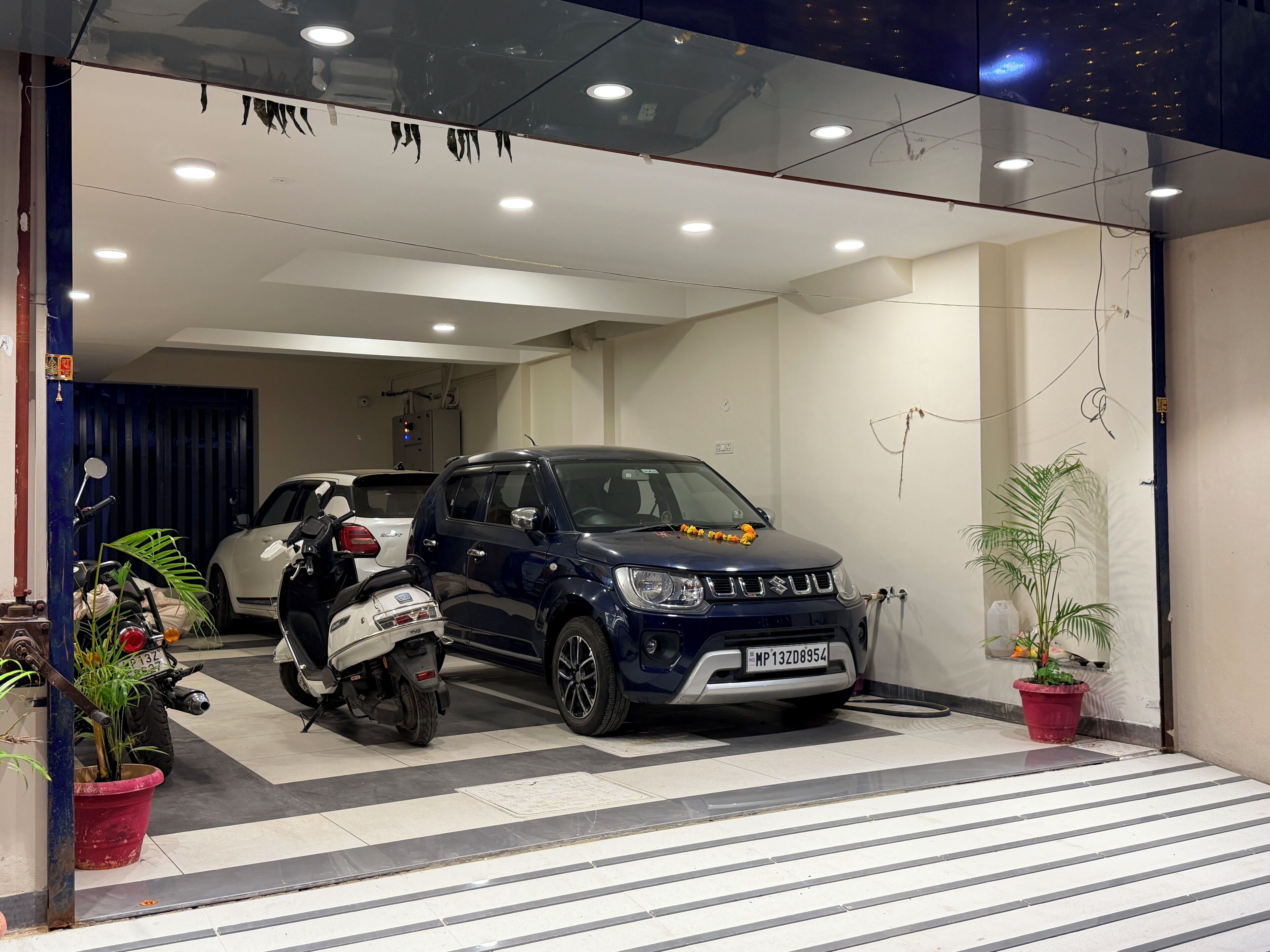 A modern building entrance with a blue car and a scooter parked inside.