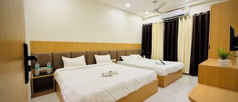A hotel room with two beds, a wooden headboard, a ceiling fan, a TV, and a small plant.