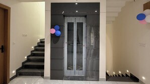 Un interior moderno con suelo de mármol, una escalera y una entrada con puerta de cristal.