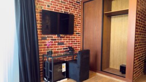 A modern room with a brick wall, a flat-screen TV mounted above a glass table, and a sliding wooden door. - ABM Green (Tangier)