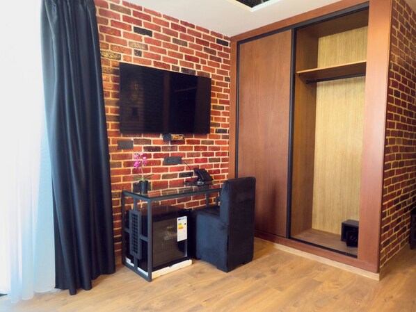 Une chambre moderne avec un mur en briques, un téléviseur à écran plat fixé au-dessus d’une table en verre et une porte coulissante en bois.