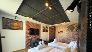 A modern hotel room with a brick wall, a large bed, a TV, and a ceiling with exposed beams and lights. - ABM Green (Tangier)