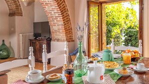 Ein Frühstückstisch mit verschiedenen Speisen, einer Vase mit Lavendel und Blick ins Grüne durch ein Fenster.
