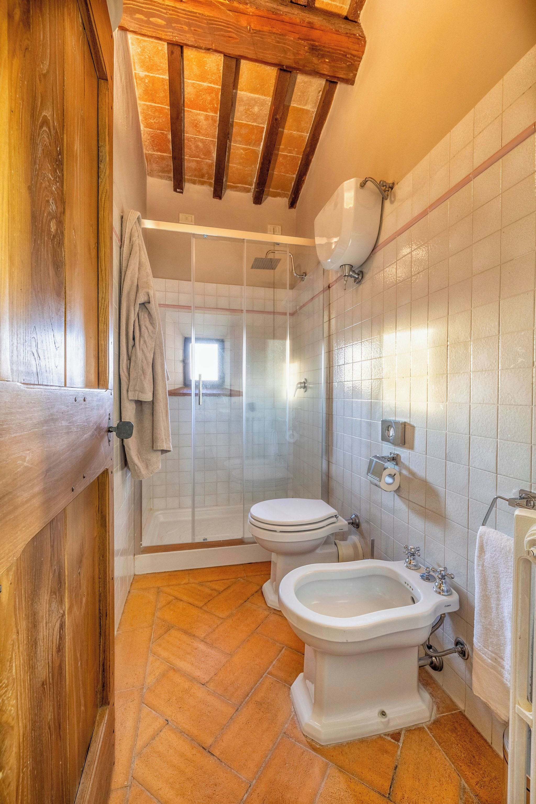 Ein Badezimmer mit Dusche, Toilette, Bidet und Fliesenwänden.