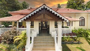A traditional building with a central staircase, a covered entrance, and a garden with various plants. - Saligao - Casa De Mello C 1863 (Saligao)