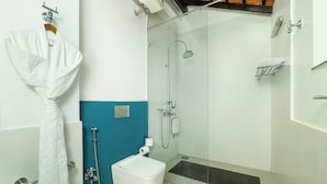 A bathroom with a glass-enclosed shower, a white toilet, and a towel rack. - Saligao - Casa De Mello C 1863 (Saligao)