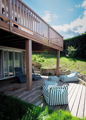 Eine Holzterrasse mit Sitzgelegenheiten und einem überdachten Bereich.