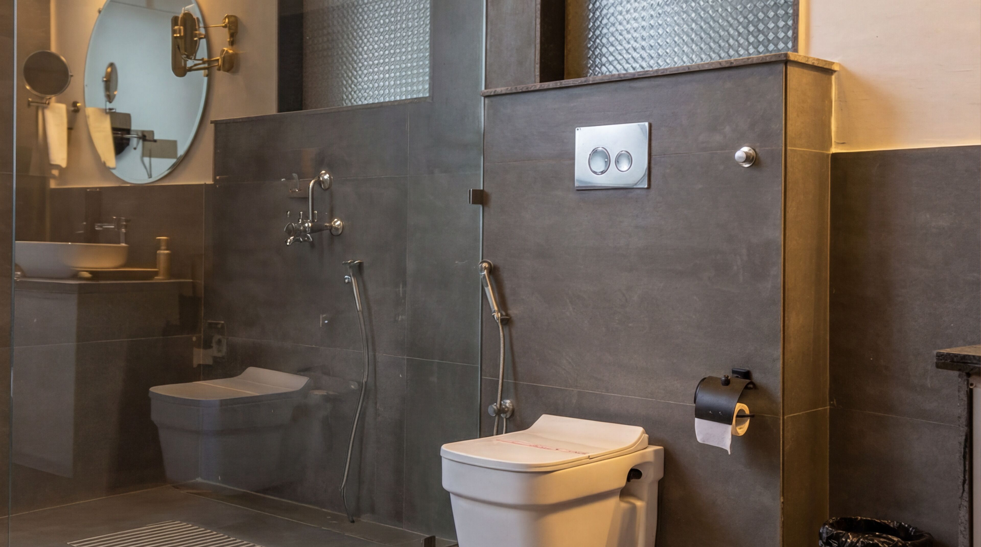A modern bathroom with a glass-enclosed shower, a toilet, and a sink.