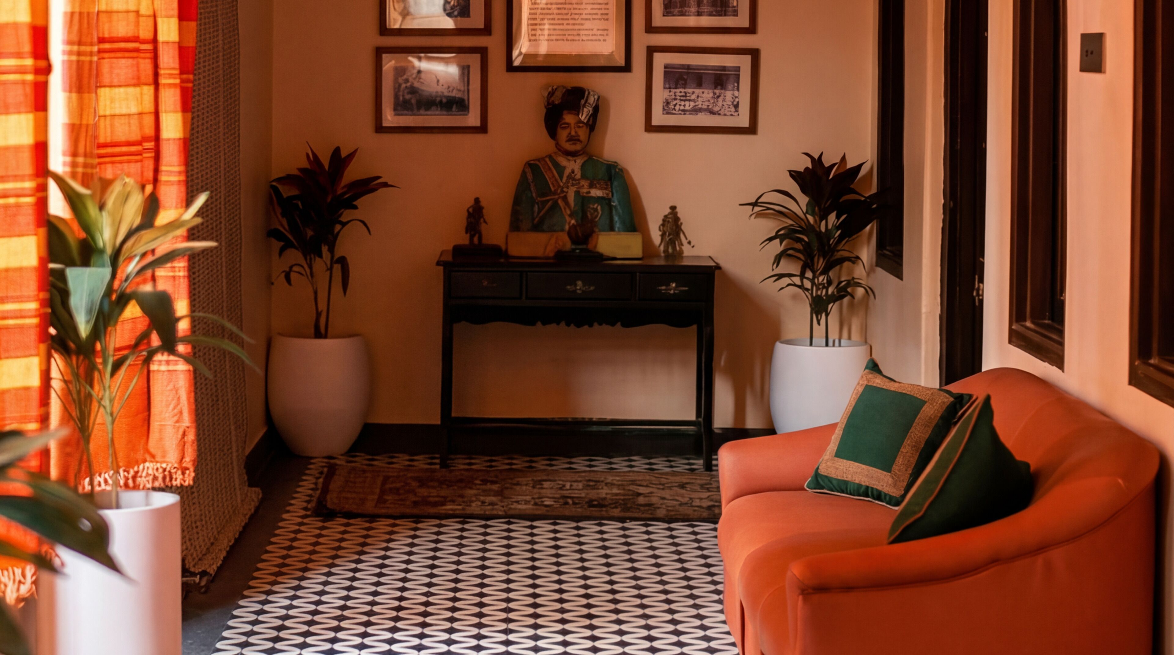 A room with a patterned floor, a sofa, a desk with a statue, and framed pictures on the wall.