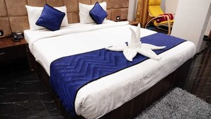 A neatly made bed with a blue and white bedspread, two blue pillows, and a white towel shaped like a swan on the bed. - BULDHANA URBAN RESIDENCY CLUB (Buldana)