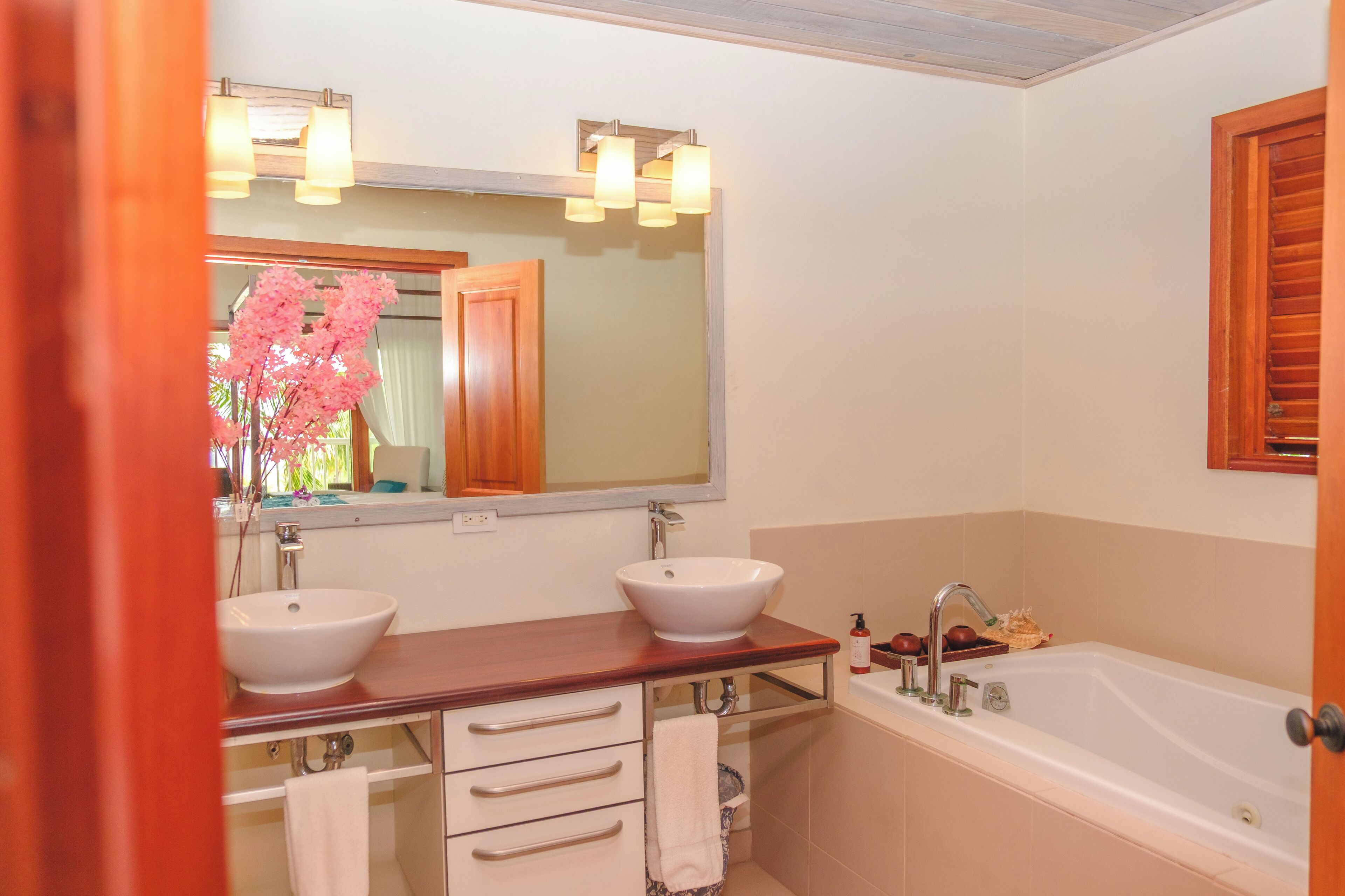 Une salle de bain avec deux lavabos, un grand miroir et une baignoire.