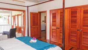 Una camera d'albergo con un letto, una sedia, porte in legno e vista su un balcone.