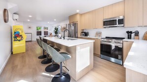 Een moderne keuken met een centraal eiland, roestvrijstalen apparatuur en houten kasten.