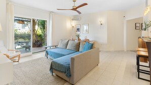 Un salón amplio con sofá, comedor y balcón con mobiliario de exterior.
