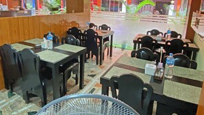 Un hall de hotel con mesas y sillas, una recepción y un restaurante visible llamado "PAN".