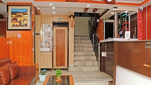 Un vestíbulo de hotel con una recepción, una escalera, un sofá y una mesa de centro.