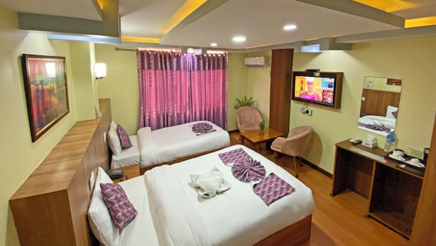Una habitación de hotel con dos camas, televisión, escritorio y espejo.