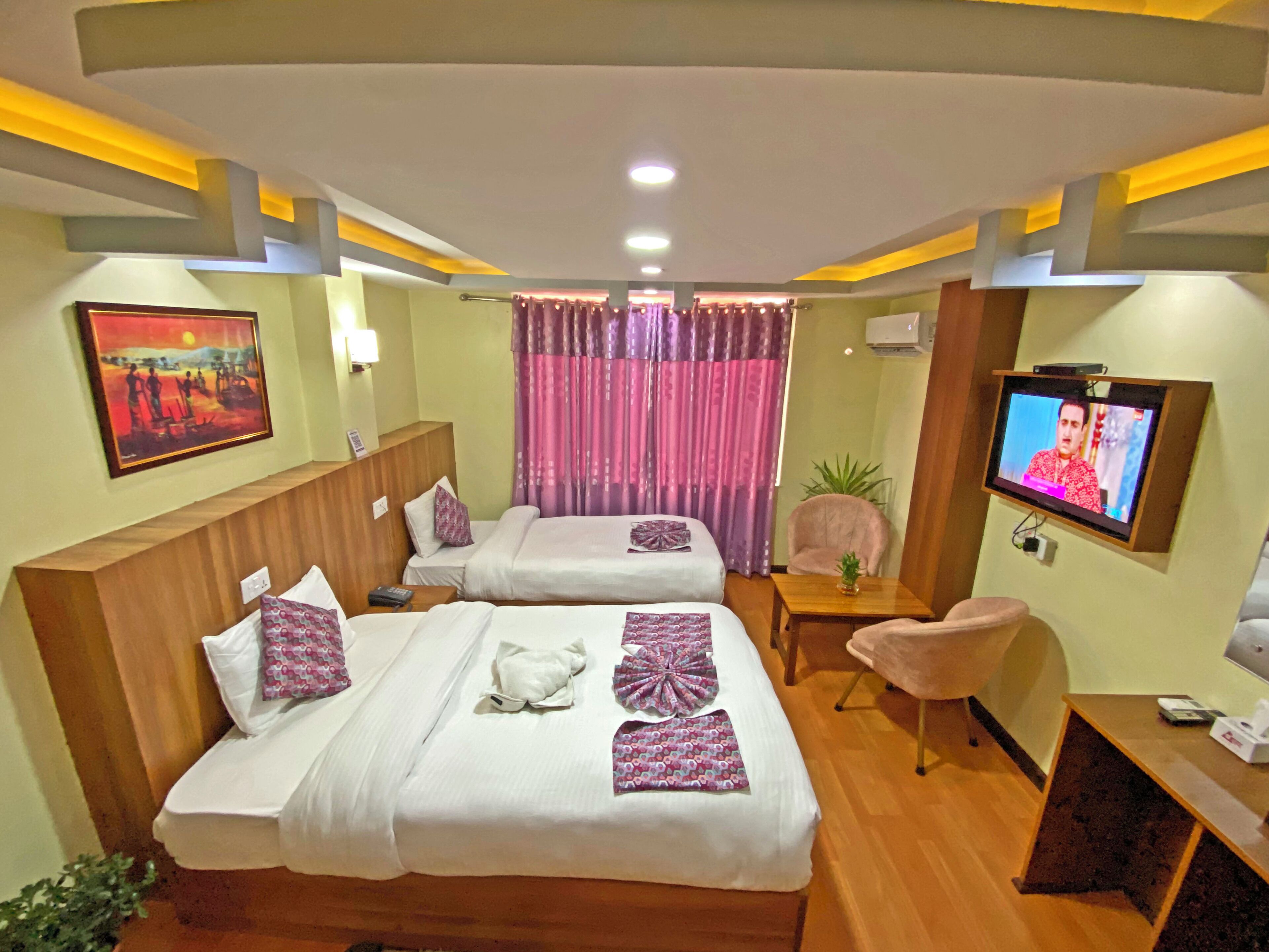 A hotel room with two beds, a TV, a small table, and a chair.