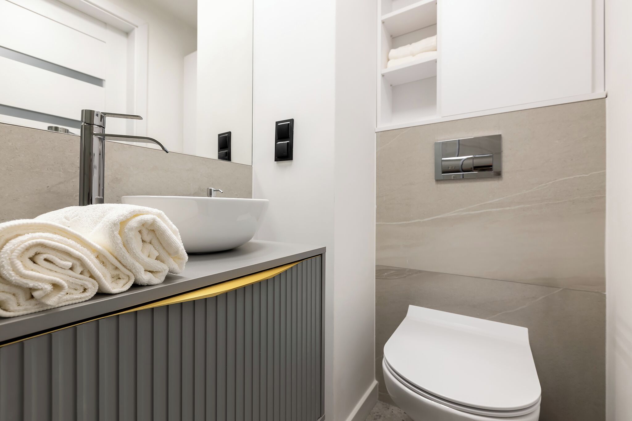 Un bagno moderno con lavandino bianco, un water e un portasciugamani.