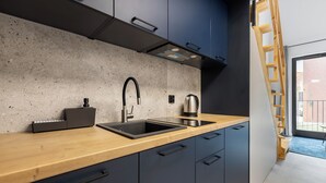 Een moderne keuken met een betegelde achterwand van beton, een roestvrijstalen spoelbak en een houten aanrechtblad.