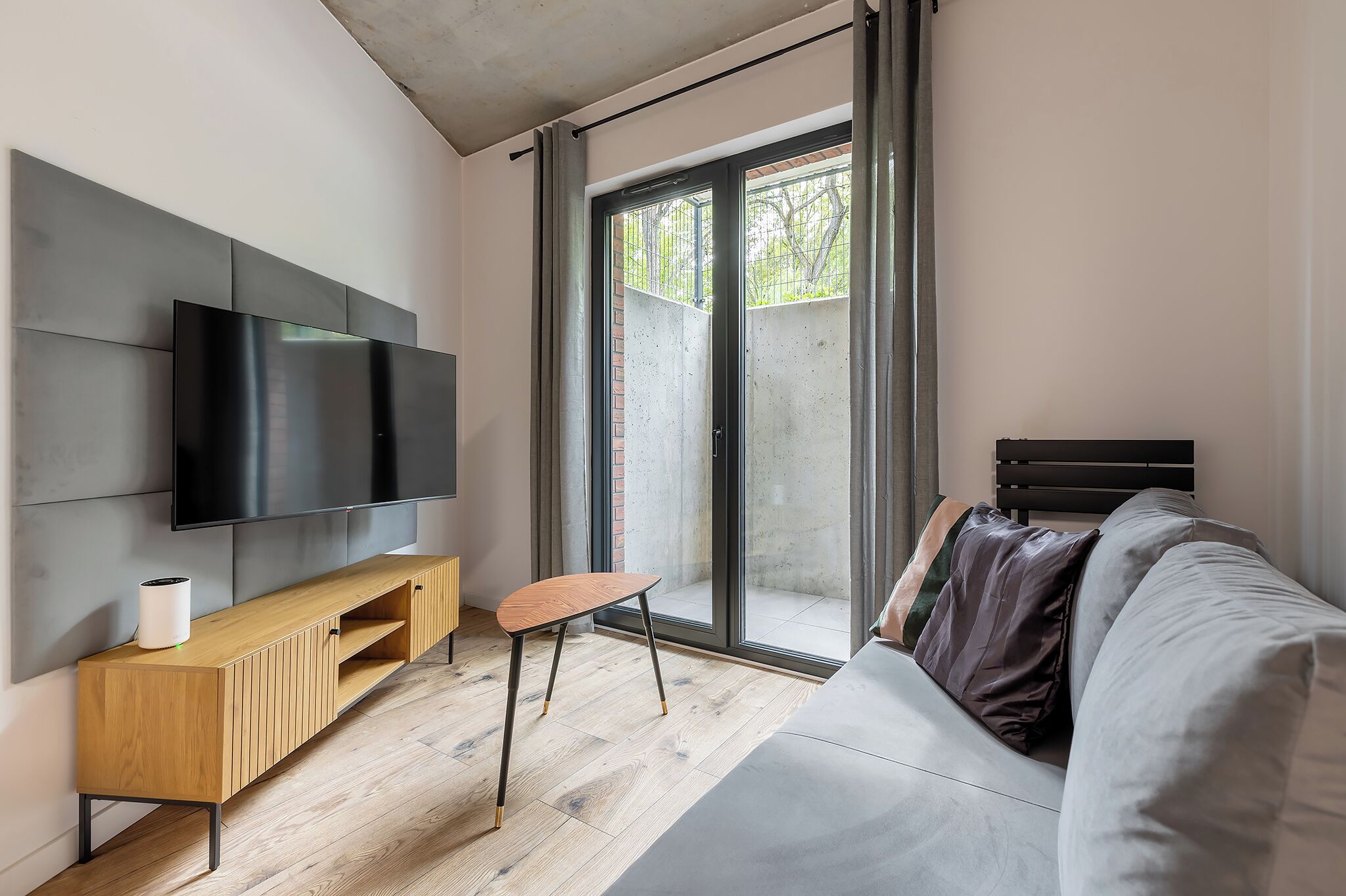 Una sala de estar moderna con televisor de pantalla plana, consola de madera y sofá.