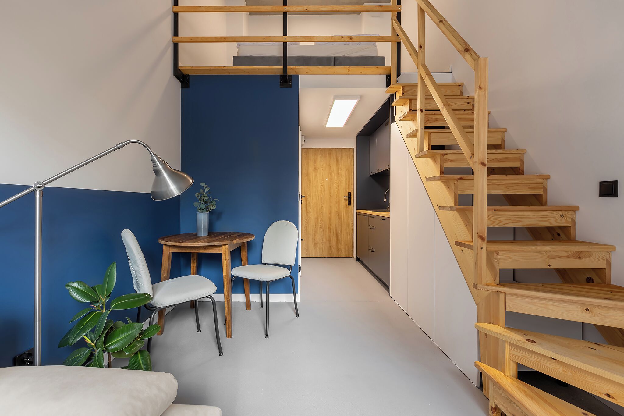 Een modern interieur met een houten trap, een eethoek met tafel en stoelen, en een plant.