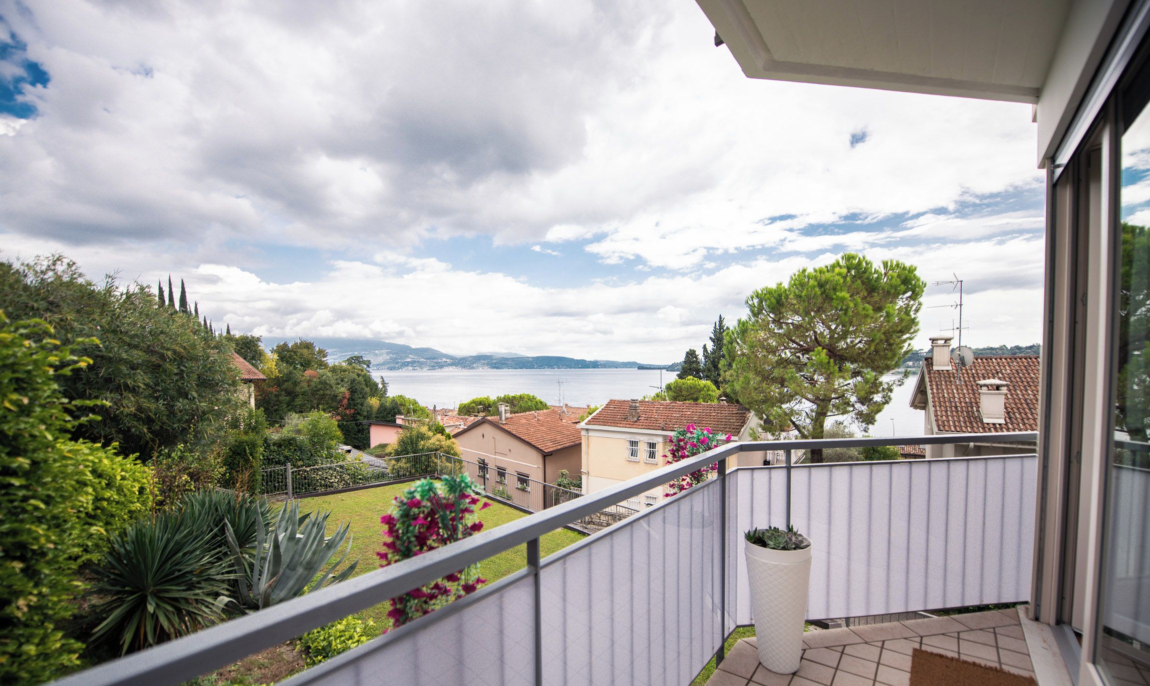 A balcony with a view of a residential area and the sea.