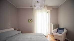 A modern bedroom with a large bed, a chair, and a window with curtains. - Sogni di Lago (Salò)