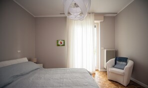 Une chambre à coucher moderne avec un grand lit, une chaise et une fenêtre avec des rideaux.