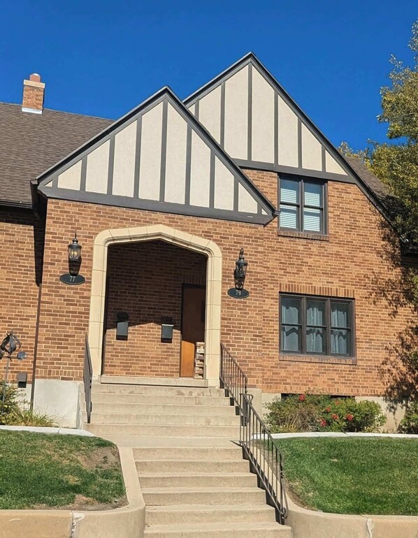 A two-story house with a prominent entrance, a brick facade, and a small front yard.