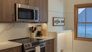 Una cocina moderna con electrodomésticos de acero inoxidable, armarios de madera y un letrero que indica barra de café.