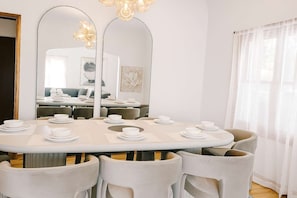 Un coin repas avec une table ronde dressée pour six personnes, entourée de six chaises.