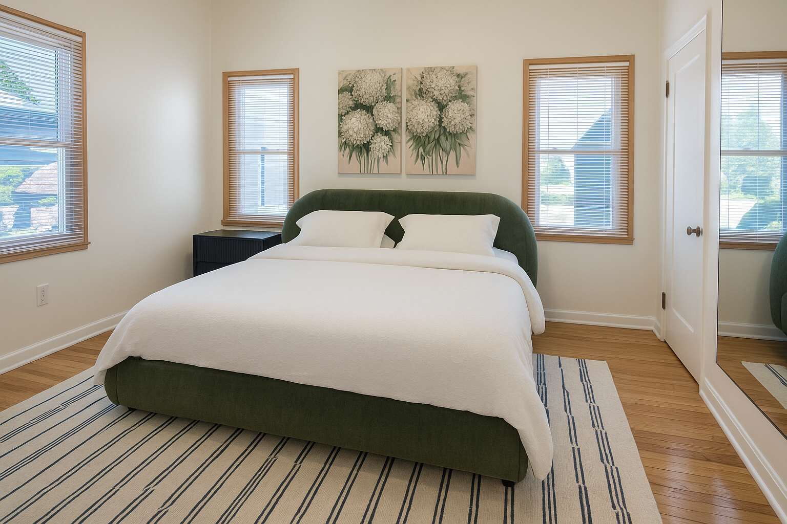 A bedroom with a bed, a nightstand, a painting, and a door.