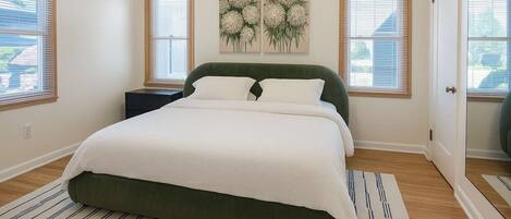 A bedroom with a bed, a nightstand, a painting, and a door.