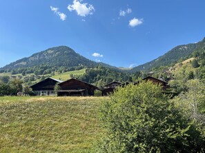 Un paysage de montagne rural, avec des cabanes en bois et un ciel bleu dégagé.