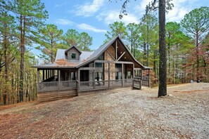 A cabin with a stone exterior, a large porch, and a covered deck area.