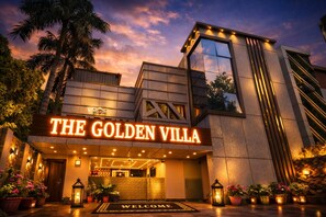 Ett hotell som heter ”The Golden Villa” och som har en modern arkitektonisk design, en inbjudande entré och en väl upplyst fasad.