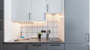 A modern kitchen with white cabinets, a granite countertop, and a stainless steel sink.