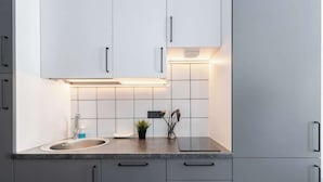 Une cuisine moderne avec des armoires blanches, un comptoir en granit et un four encastré.
