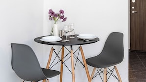 Un petit coin repas avec une table ronde, deux chaises et un vase de fleurs.
