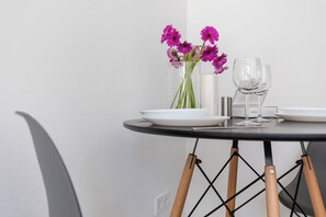 A dining table with a vase of flowers, two wine glasses, and a menu stand.