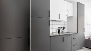 A modern kitchen with grey cabinets, a white countertop, and a sink. - River to the City Self check in (Vilnius)
