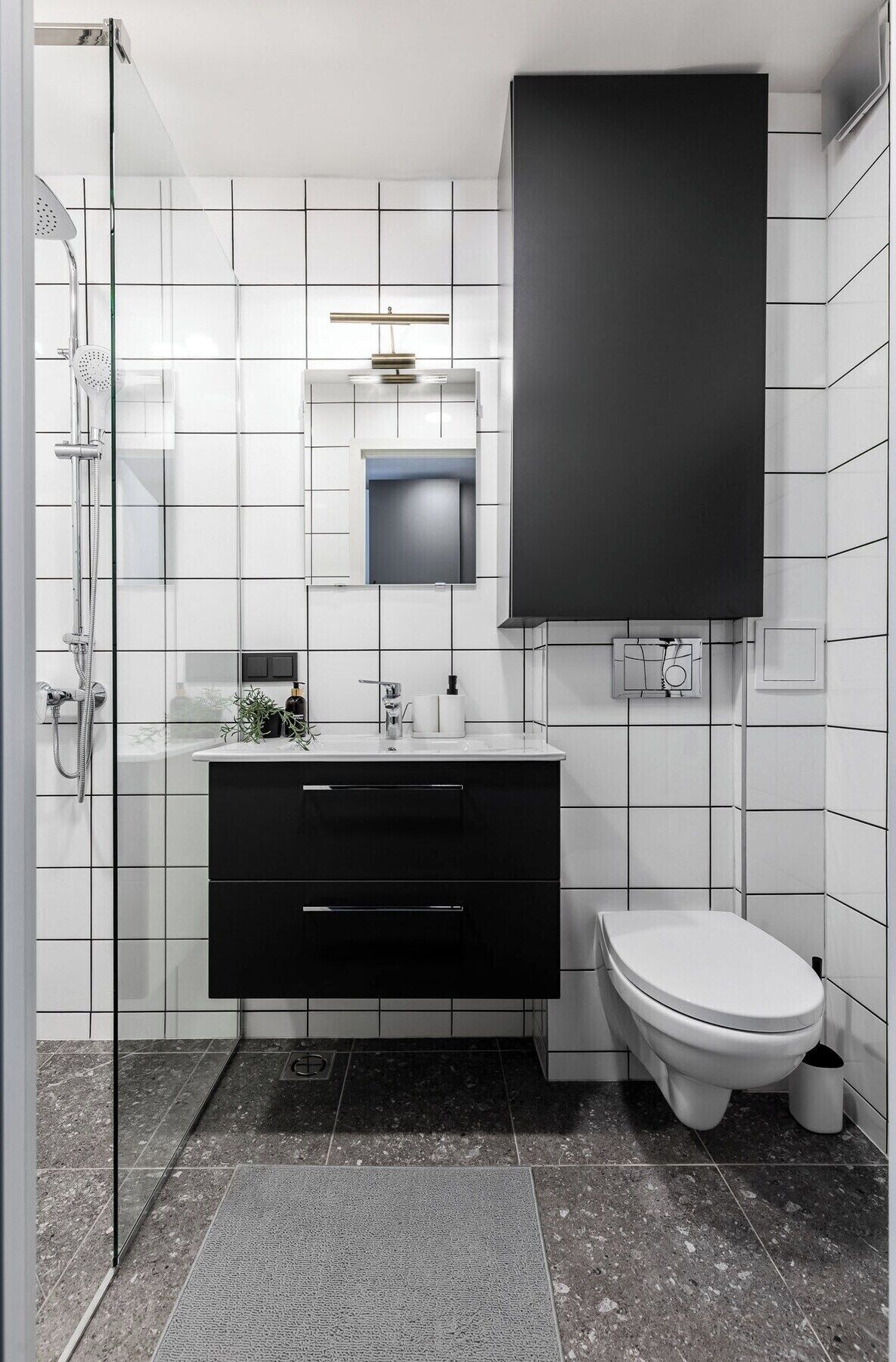 A modern bathroom with a glass shower enclosure, a black vanity with a mirror, and a white toilet.