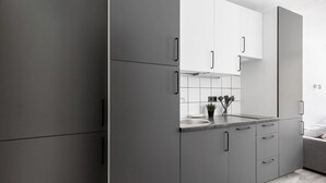 A modern kitchen with grey cabinets, a white countertop, and a small potted plant.