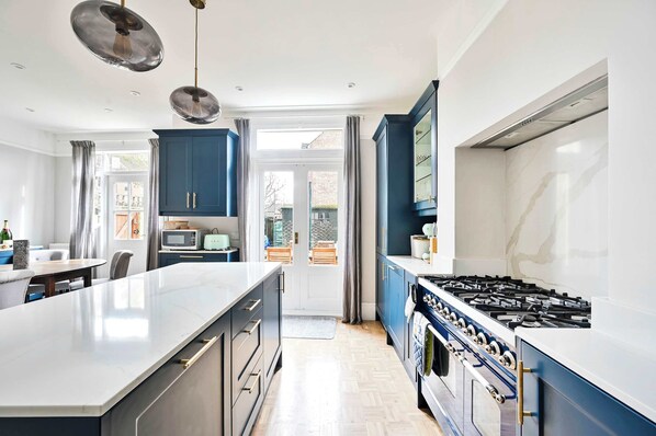 Une cuisine moderne dotée d’un îlot central, de meubles bleus, d’une cuisinière à gaz et d’un four à micro-ondes.