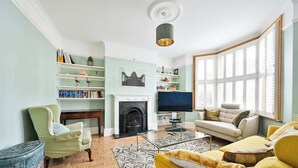 A living room with a fireplace, television, and a sofa. - Charming Two-Bedroom Home in London (Greater London)