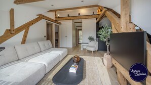 Ein modernes Wohnzimmer mit Sofa, Couchtisch und einem Flachbildfernseher auf einem Holzboden.