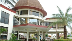A modern hotel with a distinctive dome-shaped roof, multiple balconies, and a well-maintained garden with palm trees. - Splendid 2 Bedroom in Tivoli Garden Residences, high floor, spacious, balcony (Mandaluyong City)
