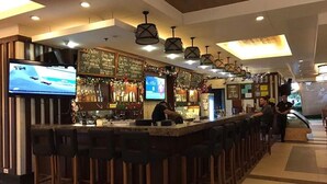 A bar area with multiple stools, a television screen, and various bar equipment. - Splendid 2 Bedroom in Tivoli Garden Residences, high floor, spacious, balcony (Mandaluyong City)